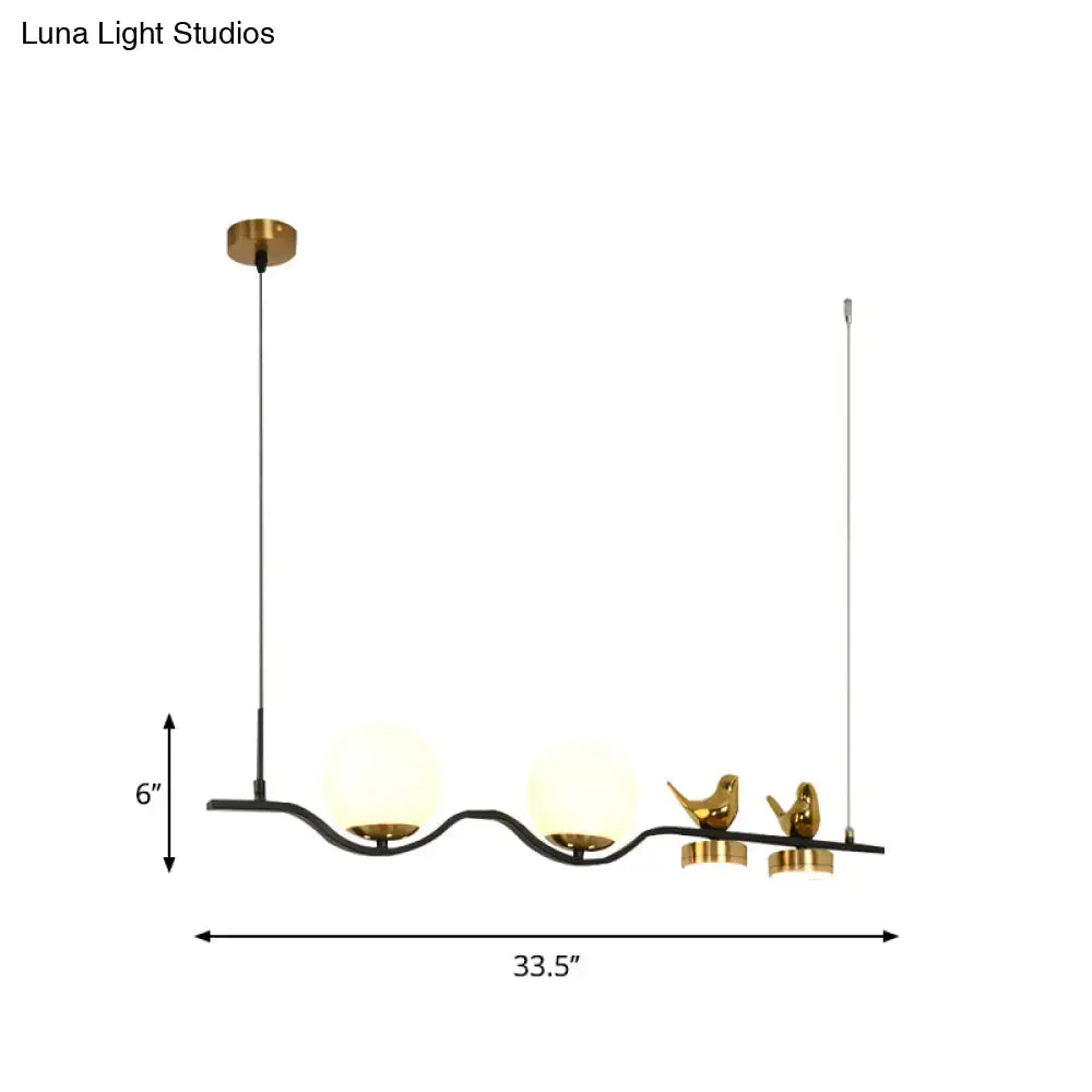 Gold-toned bird-themed pendant light with frosted glass globes and black curved arm for branch dining room island use
