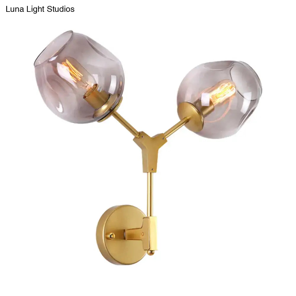 Contemporary gold-toned wall sconce with two frosted glass globes and clear glass shade for light wall decor