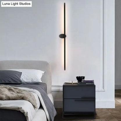 Contemporary black slim wall light with sleek vertical design providing warm natural light for bedroom ambiance