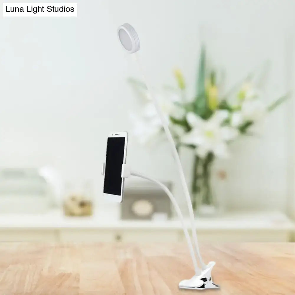 White flexible led desk lamp with clip-on base and adjustable arm holding smartphone for bedroom use