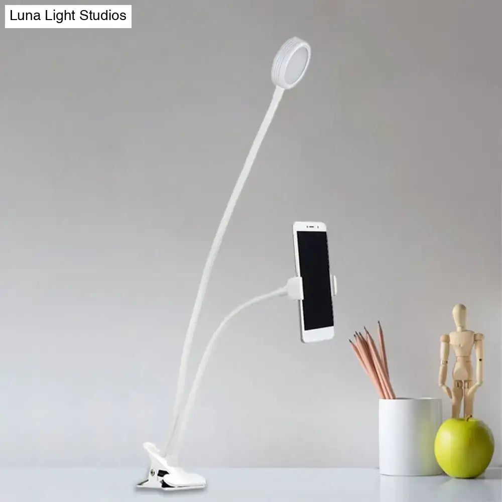 White flexible LED desk lamp with clip base and phone holder designed for contemporary black and white bedroom use