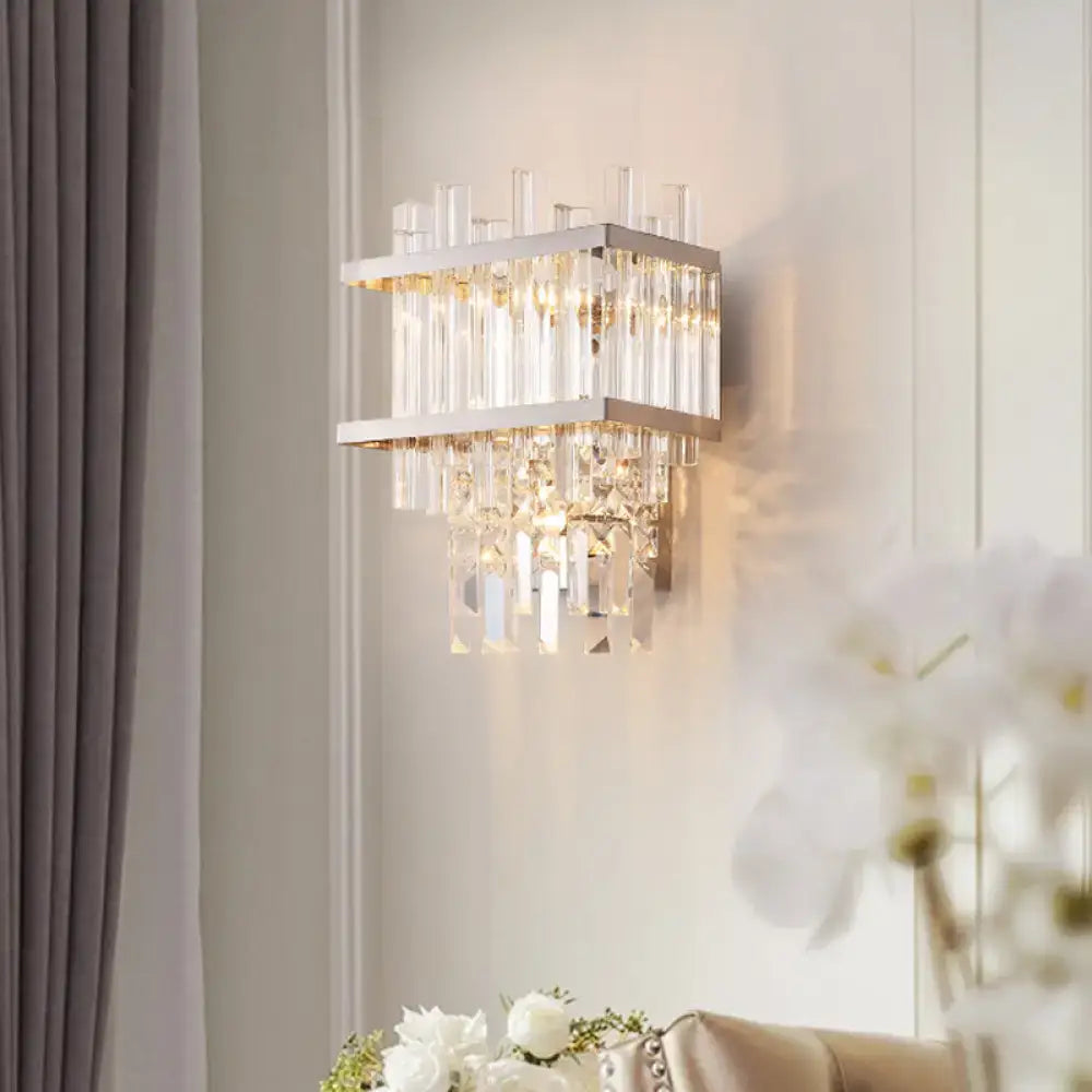 A contemporary brass chrome wall lamp with a sleek silver frame and cascading clear crystal rods for dining room use
