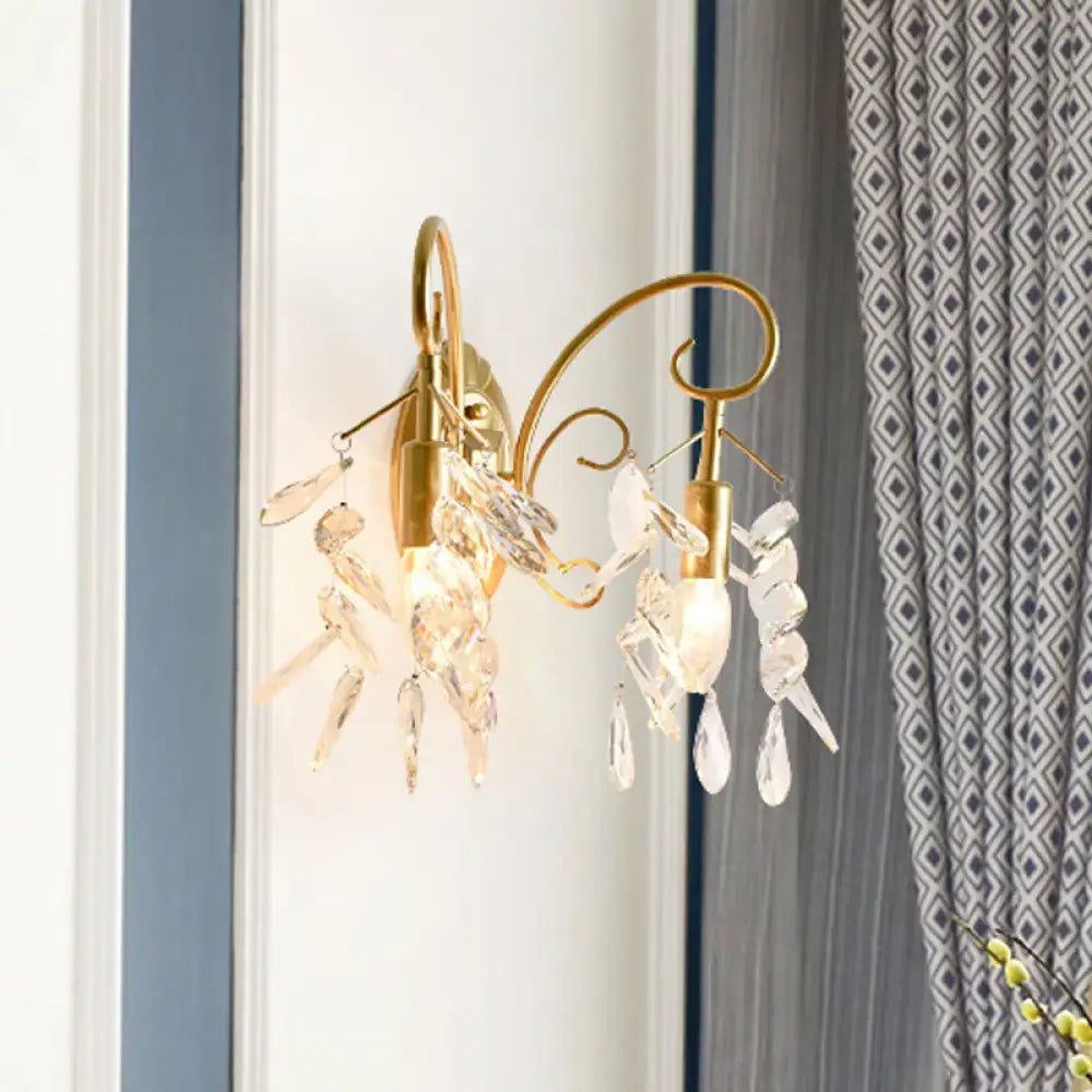 Contemporary brass wall mount light with gold-toned curved arms and dangling clear teardrop crystal wall pendants