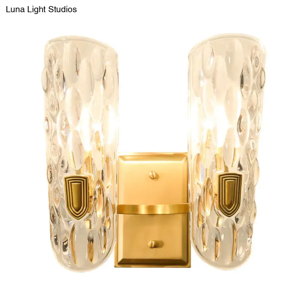 Contemporary brass water glass wall sconce with gold finish and textured clear water glass shades for bedroom bedside light
