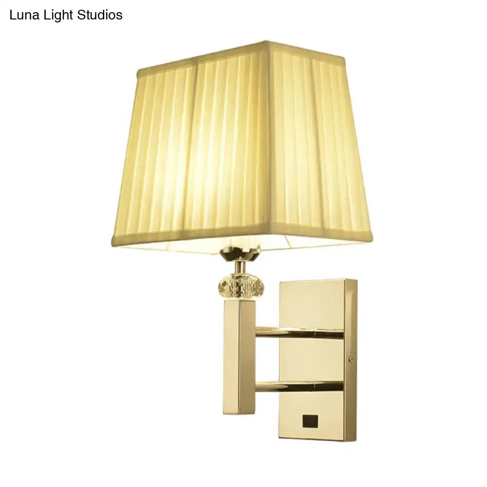 Contemporary gold-toned wall sconce light fixture with cream pleated lampshade crystal accent and spot light feature