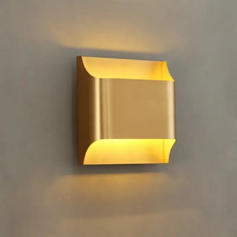 Contemporary copper brass wall sconce in gold with sleek metallic finish and curved edges for living room decorbites