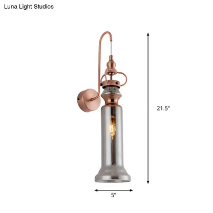 Contemporary copper wall sconce with tall cylindrical smoke gray amber glass shade and exposed filament bulb for bedroom lighting