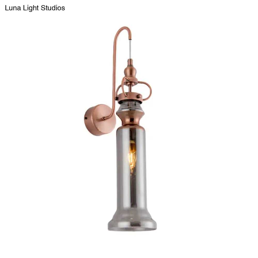 Contemporary copper wall sconce with smoke gray amber tall cylindrical glass shade and exposed filament bulb for bedroom light