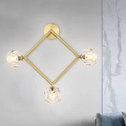 Contemporary gold brass wall light fixture with geometric design and three faceted crystal shades for bedroom use