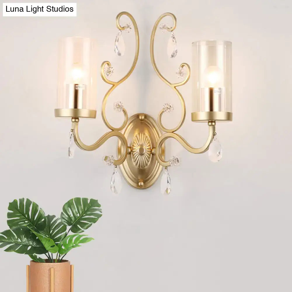 Contemporary gold-toned wall light with clear glass cylinder shades and crystal droplets for bedroom use
