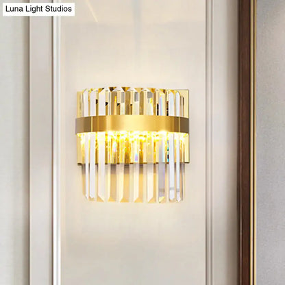 Contemporary gold-toned demilune cylinder wall light with vertical crystal prisms and central illuminated band for living room