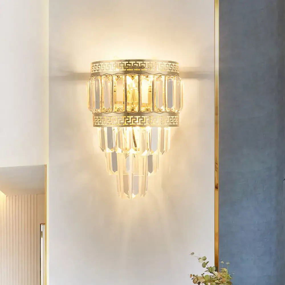 Contemporary gold wall lamp with clear crystal prisms and greek key pattern detailing for bedroom light fixture