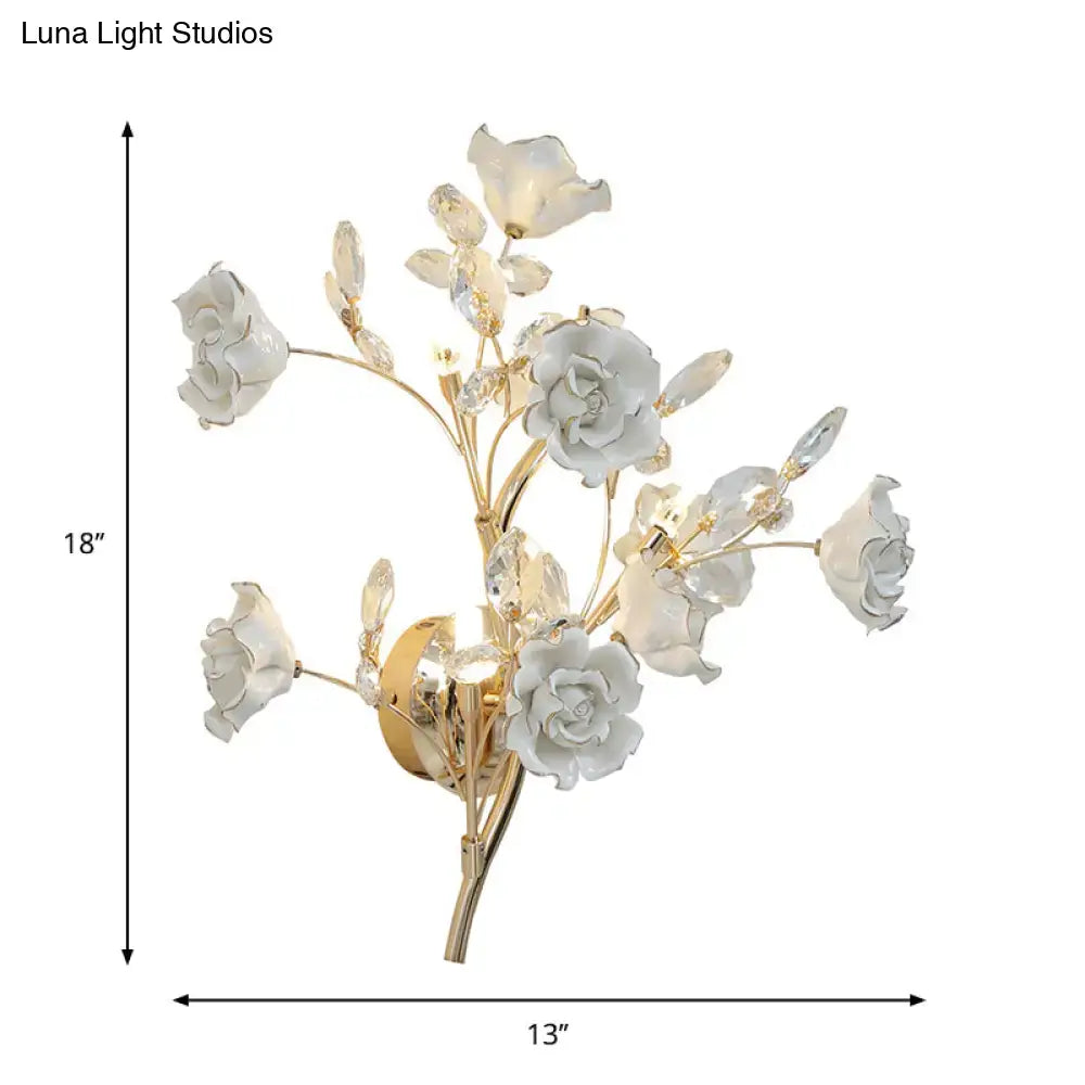 Elegant white porcelain rose wall lamp with gold-toned branches and crystal accents for contemporary bedroom light fixture