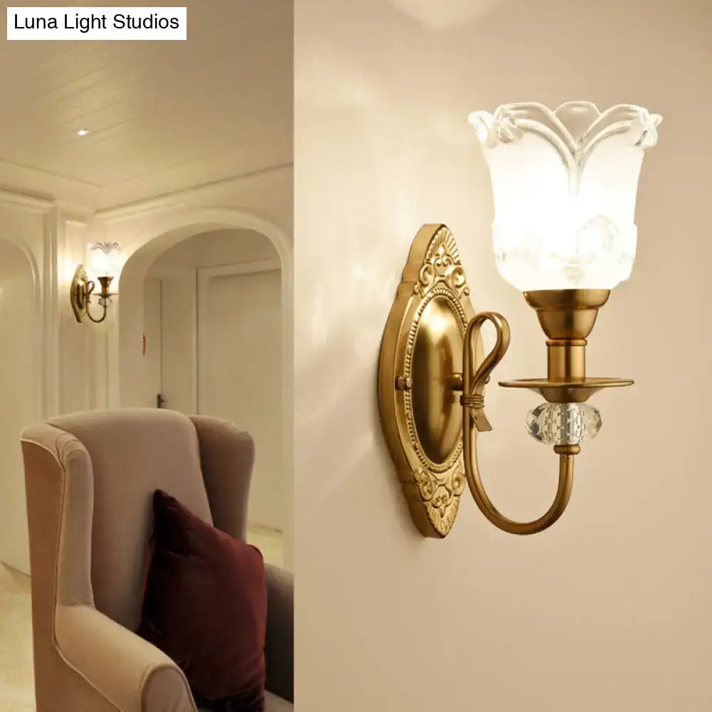 Antique brass wall lamp featuring a frosted glass petal flower-shaped shade and faceted crystal accent for bedroom use