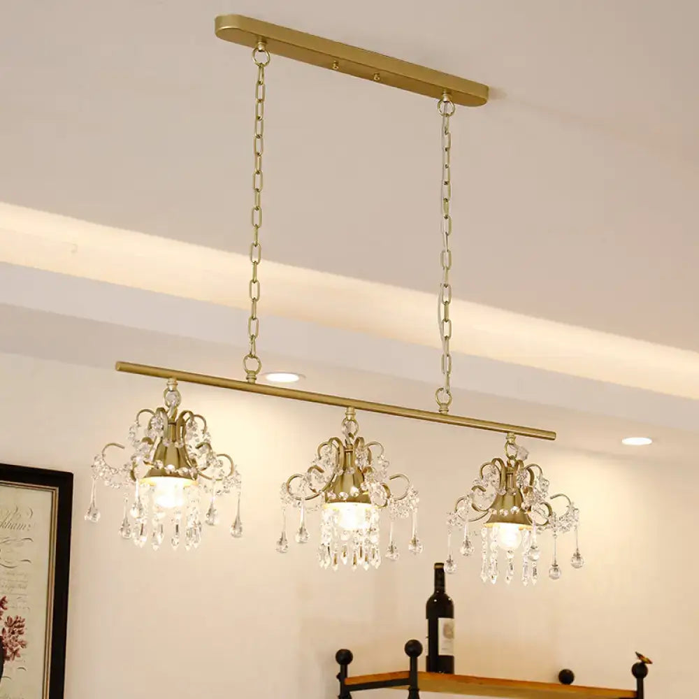 Gold-toned decorbites contemporary island chandelier with three crystal pendant lights and ornate scroll frame design