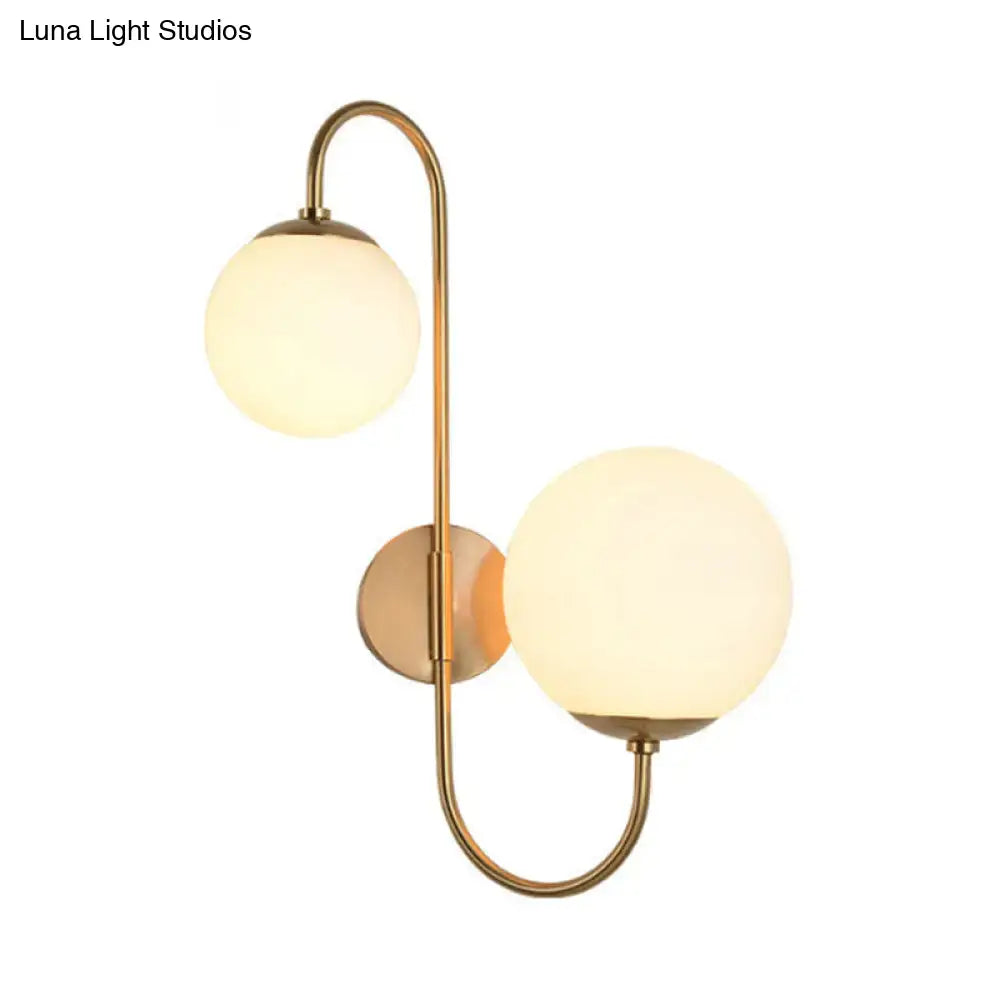 Brass-finished contemporary opal glass wall sconce light with two frosted glass globe shades for bedroom use