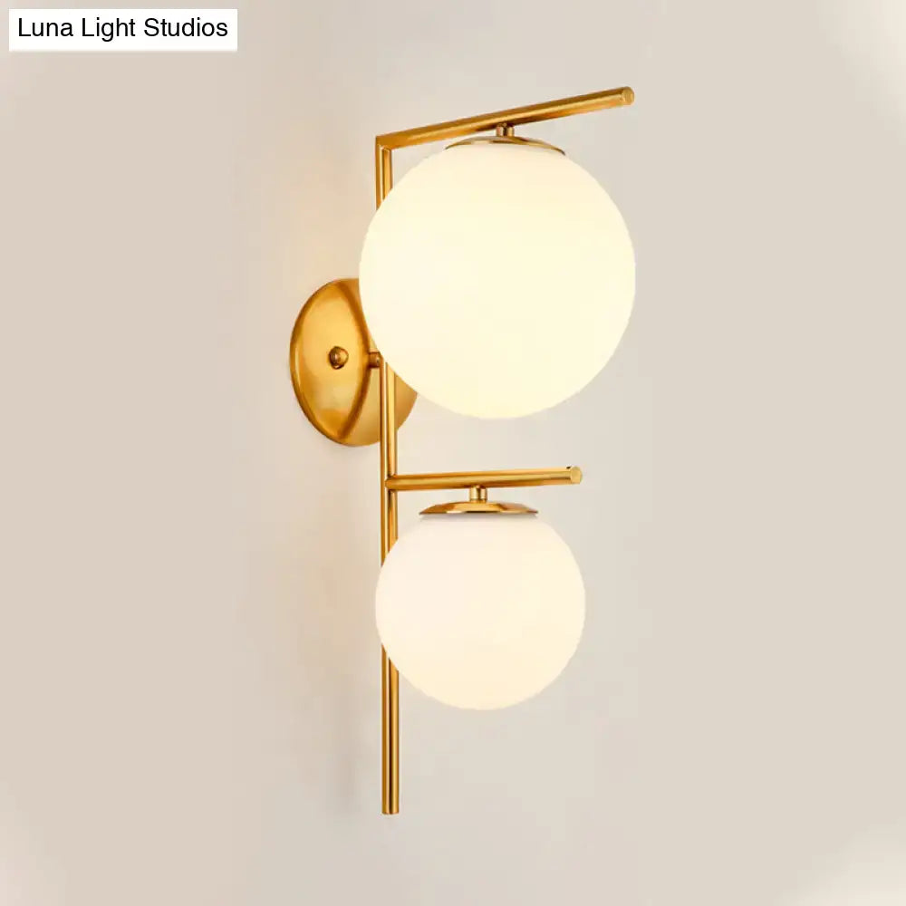 Contemporary gold light fixture with two frosted spherical glass shades featuring an elegant shade width for bedrooms