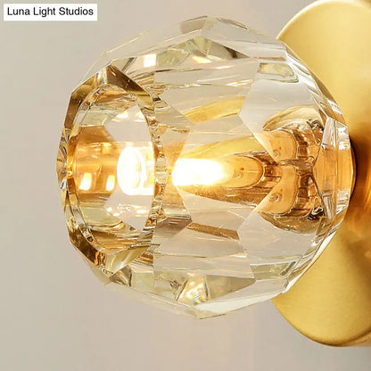 Contemporary golden wall mount lamp with faceted glass shade emitting a warm golden glow for living room use