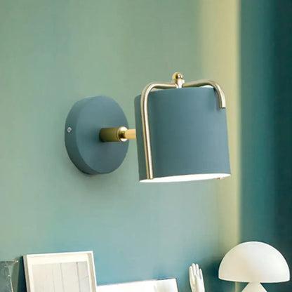 Contemporary green grey sconce featuring a blue cylindrical wall light with brass-finished metal frame for bedroom use