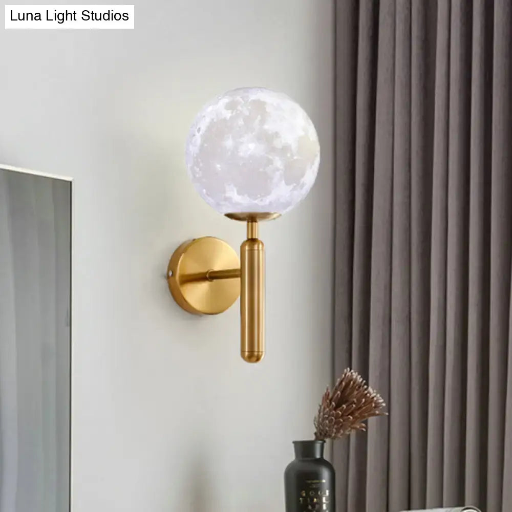 Contemporary white glass wall fixture featuring a gold-toned sconce with a translucent moon-patterned globe for bedrooms