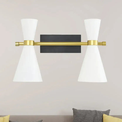 Contemporary wall sconce with adjustable arm featuring a sleek brass bar, black backplate, and white conical shades