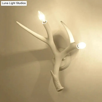 Contemporary white resin antler wall sconce with two illuminated candle-style bulbs for restaurant dining room use