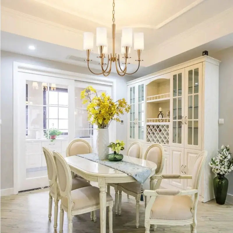 Decorbites copper ceiling chandelier with white fabric shades beside a tall white ceramic vase holding bright yellow flowers