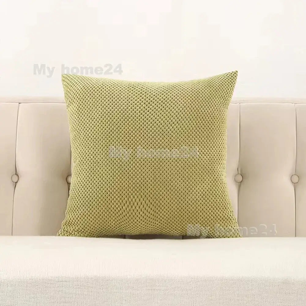 A square light green corduroy corn kernel throw pillow with textured woven pattern on a beige tufted sofa decorbites corduroy corn