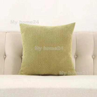 A square light green corduroy corn kernel throw pillow with textured woven pattern on a beige tufted sofa decorbites corduroy corn