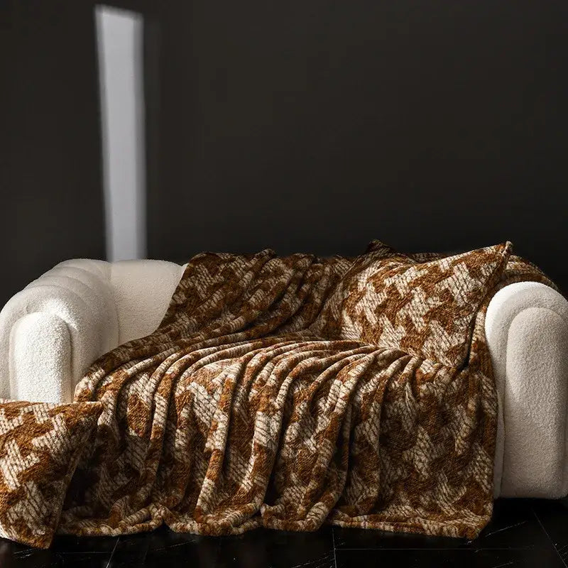 A cosy faux rabbit plush floral throw blanket in warm brown and cream geometric pattern draped over white sofa decorbites cosy faux