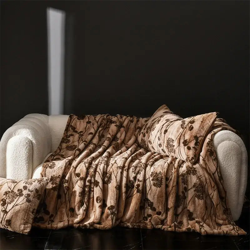 A cosy faux rabbit plush beige throw blanket with dark brown floral pattern draped over white couch decorbites cosy faux