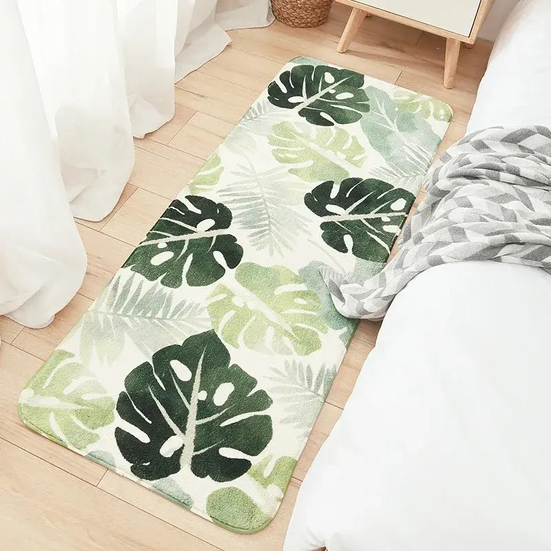 A plush rectangular bedside rug with vibrant green tropical leaves on cream decorbites cozy faux lamb wool material