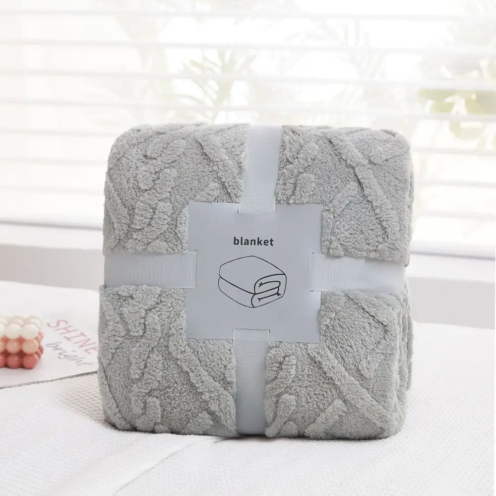 A soft light gray decorbites cozy jacquard plush blanket with textured pattern wrapped in white ribbon for sofa decor