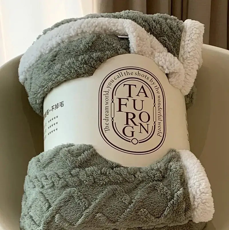 A cozy gray and white coral fleece blanket with textured pattern wrapped in branded packaging for bedroom use