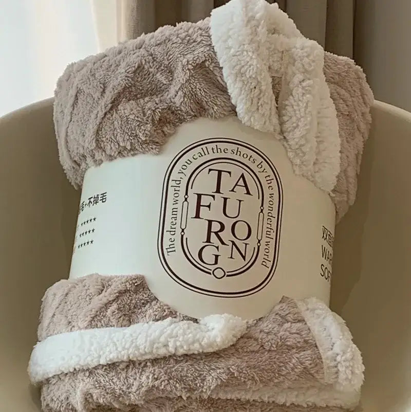 A cozy mustard and white coral fleece blanket with plush sherpa texture wrapped in branded packaging