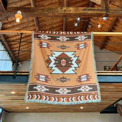 A tan and brown geometric nordic camping blanket with fringed edges and a central light blue diamond motif for cozy nordic decorbites living room decor