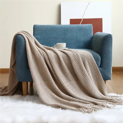 Beige cozy nordic knit textured tassel throw blanket draped over blue armchair for nordic knit sofa decorbites cozy nordic