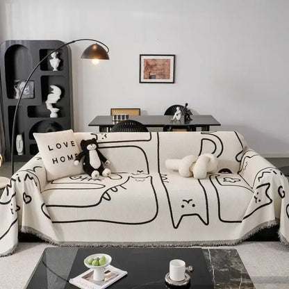 Cream-colored chenille sofa cover with black line-drawn cat illustrations and fringed edges for living room use