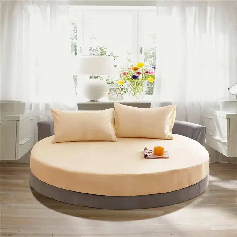Cream and gray round fitted bed sheet set on a cream-colored round fitted bed with gray base and matching pillows