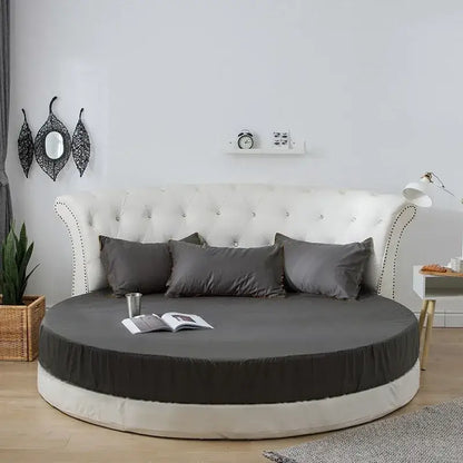 Round fitted bed with tufted white headboard and cream and gray bed sheet set for elegant bedroom decor
