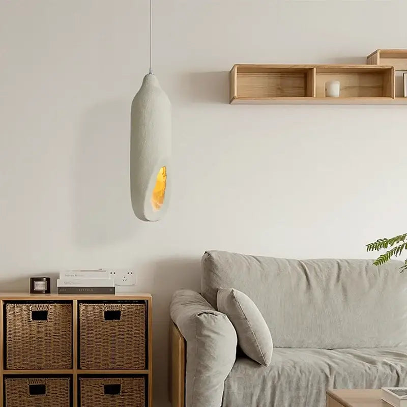 Cream ceramic pendant light with smooth elongated oval shape and warm yellow glow by decorbites cement handmade