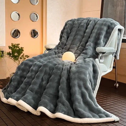 A plush dark gray decorbites cozy bubble faux rabbit fur blanket with quilted texture and white fleece lining draped over a chair