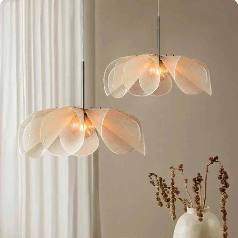 Delicate cream fabric flower chandelier with translucent layered petal shades suspended by metallic rods for dining room