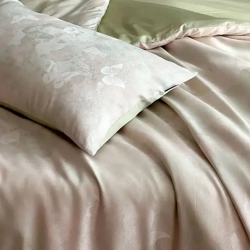 A blush-pink satin pillow sham with butterfly floral pattern in a cream floral cotton jacquard bedding set