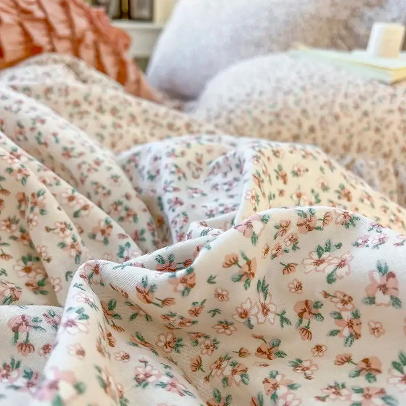 Cream-colored bedding set with double layer lace ruffles featuring a delicate pink and green floral pattern