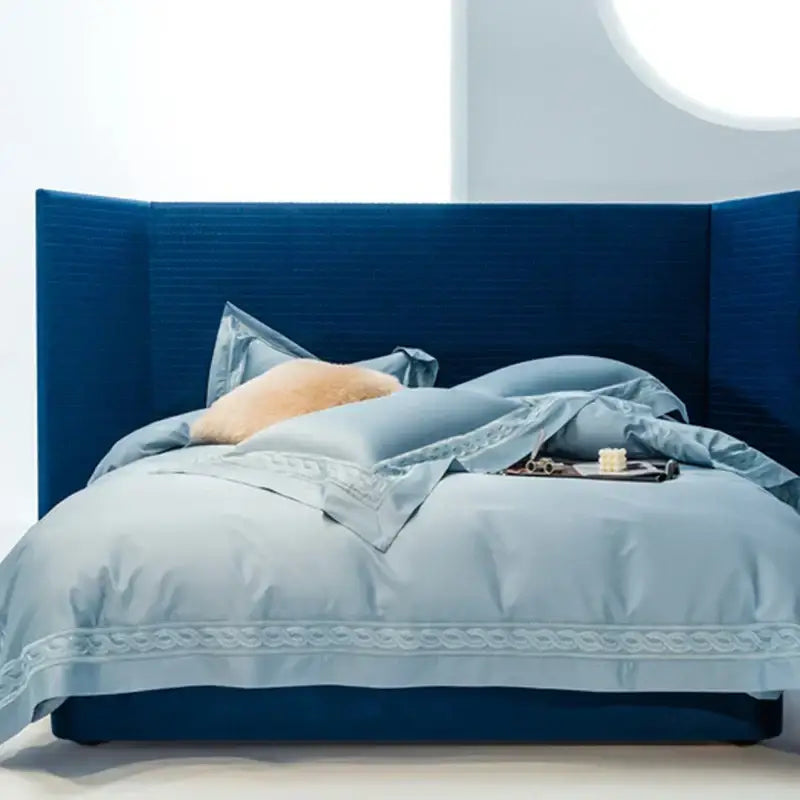Blue upholstered bed with matching headboard and light blue satin decorbites bedding set with wide edge embroidery available in two sizes