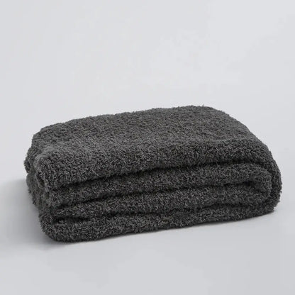 A plush dark gray knitted throw blanket with a soft ribbed microfiber surface suitable for bedroom use