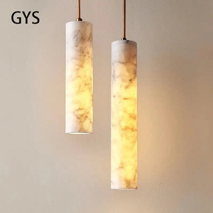 Two cream marble cylindrical pendant lights with golden veining featuring warm glowing interiors ideal for luxury decorbites decor