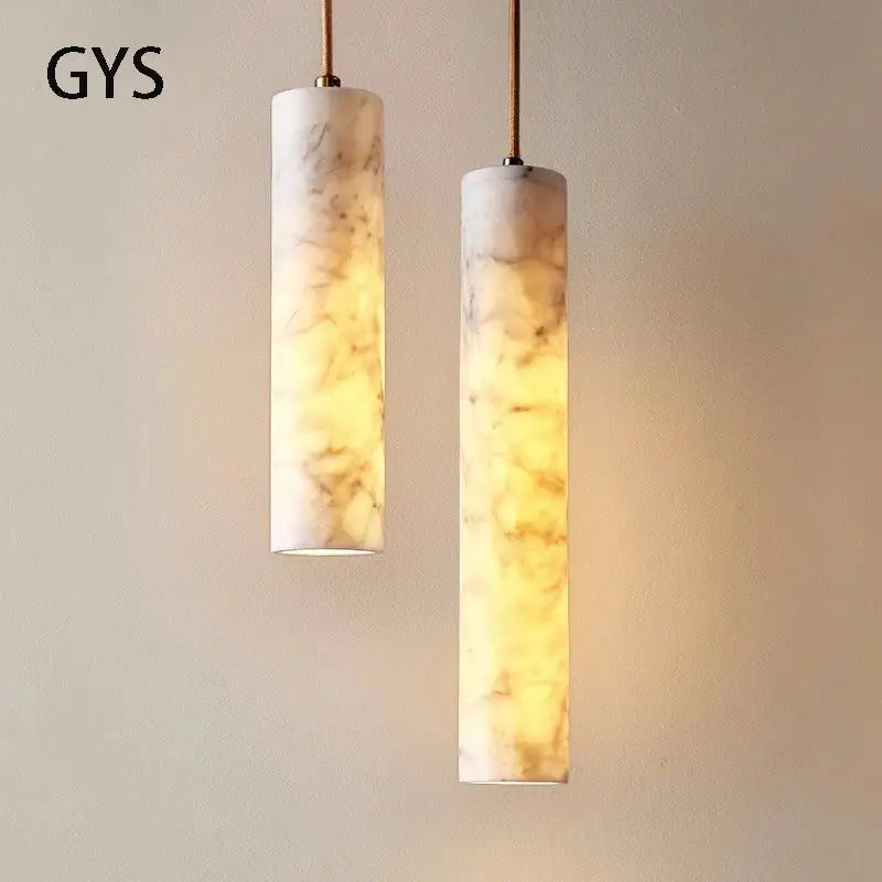 Two cream marble cylindrical pendant lights with golden veining featuring warm glowing interiors ideal for luxury decorbites decor