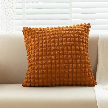 A warm orange elastic puff plaid cushion cover with raised grid texture on a light sofa for living room decor